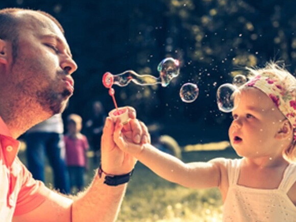 Dad and baby daughter playing with soap bubbles