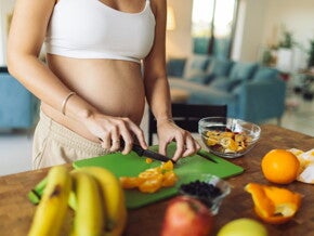 Zwangere vrouw die fruit snijdt in de keuken