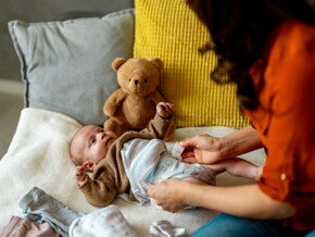 Femme change la couche d’un bébé sur un lit