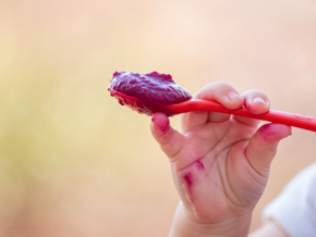 Bébé tient une cuillère avec purée betterave bébé