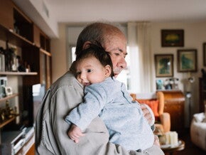Un grand-père fait un câlin à un bébé dans le salon