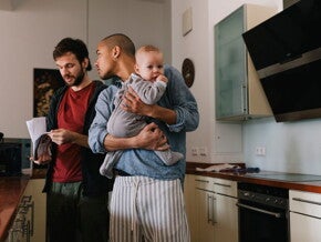 Deux hommes dans la cuisine, dont l’un tient un bébé