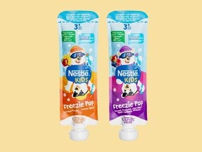 Twee knijpzakjes Nestlé Kids Freezie Pop, oranje en paars, op een gele achtergrond.