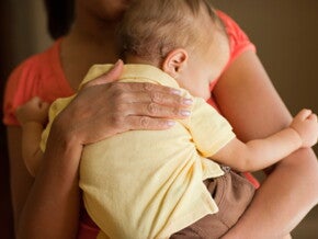 Volwassene houdt een baby rechtop tegen de schouder