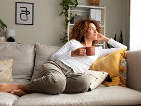 Une femme se détend sur le canapé avec une tasse à la main