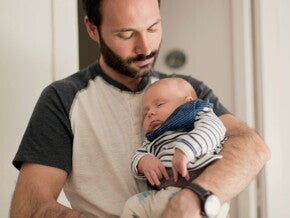 Un homme tient un bébé endormi dans ses bras