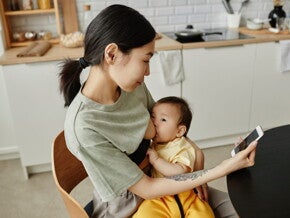 Een moeder geeft haar baby borstvoeding in de keuken