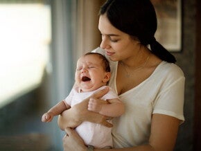 Moeder houdt haar huilende baby troostend in haar armen