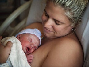 Moeder houdt haar pasgeboren baby huid-op-huid vast in het ziekenhuis