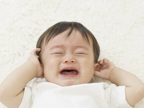 Un bébé pleure en se tenant les oreilles – Nestlé FamilyNes
