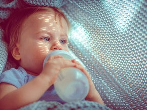 Baby drinkt een flesje melk in een hangmat – Nestlé FamilyNes