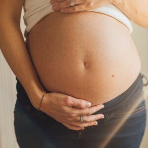 Une femme enceinte soutient son ventre avec sa main