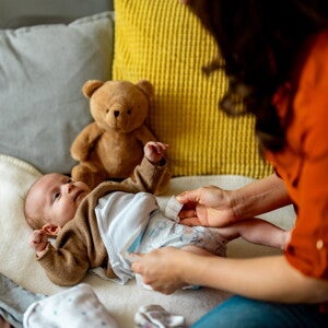 Femme change la couche d’un bébé sur un lit