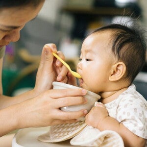 Femme donne de la compote à un bébé avec une cuillère