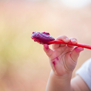 Baby houdt een lepel met groentepap rode biet vast
