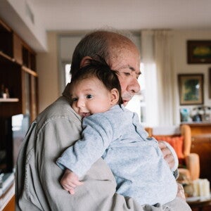 Un grand-père fait un câlin à un bébé dans le salon