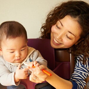 Une mère aide son bébé à manger avec une cuillère