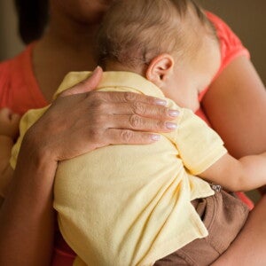 Un adulte tient un bébé droit contre son épaule