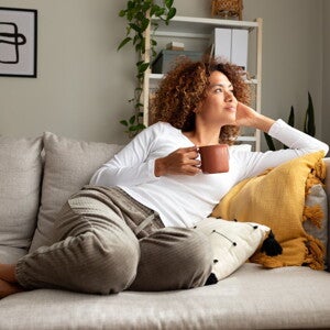 Une femme se détend sur le canapé avec une tasse à la main