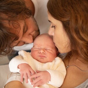 Een man en een vrouw kussen hun baby