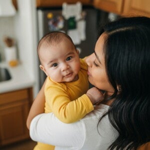 Une femme tient son bébé souriant dans ses bras – Nestlé FamilyNes