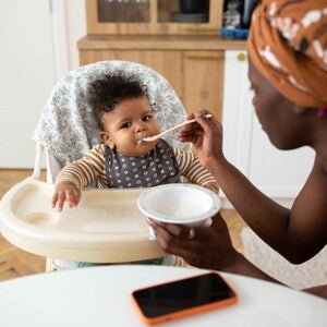 Une mère nourrit son bébé dans une chaise haute avec une cuillère