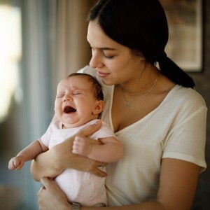 Moeder houdt haar huilende baby troostend in haar armen