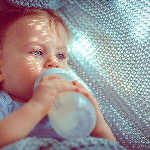 Baby drinkt een flesje melk in een hangmat – Nestlé FamilyNes