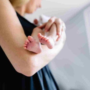 Une femme tient son bébé qui a des régurgitations – Nestlé Baby&Me Une femme tient son bébé qui a des régurgitations – Nestlé Baby&Me