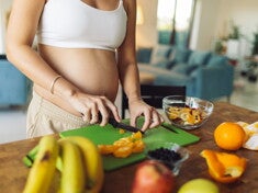 Zwangere vrouw die fruit snijdt in de keuken