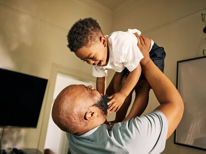 Zwangere vrouw met babykleding en babyschoenen op bed - Nestlé FamilyNes
