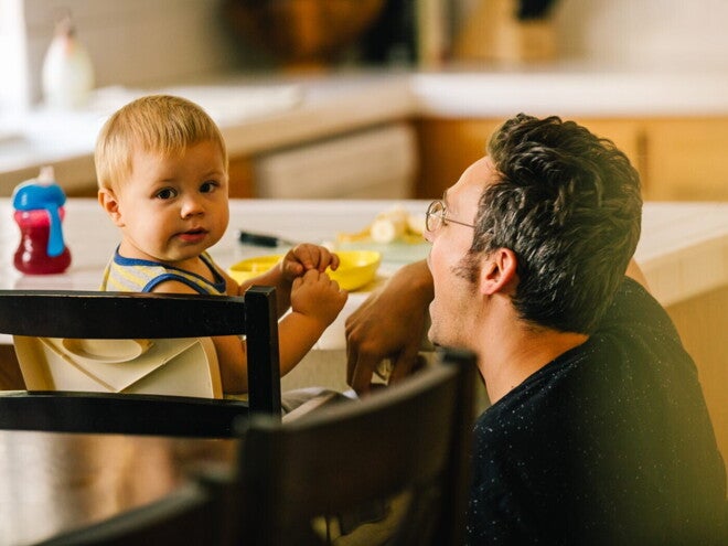Bébé assis dans une chaise haute, accompagné d'un homme