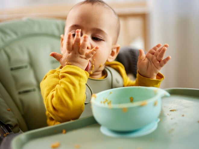 Baby die groentepap eet in een kinderstoel