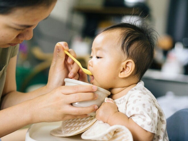 Femme donne de la compote à un bébé avec une cuillère