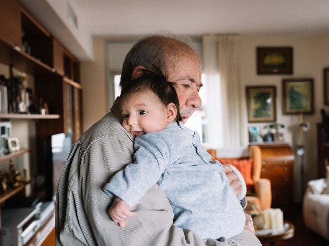 Grootvader knuffelt een baby in de woonkamer