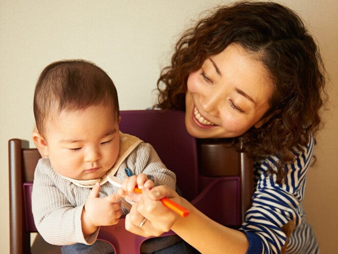 Une mère aide son bébé à manger avec une cuillère