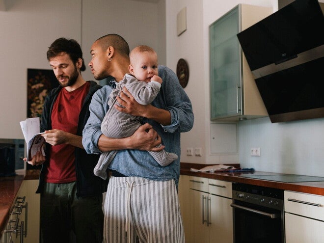 Deux hommes dans la cuisine, dont l’un tient un bébé