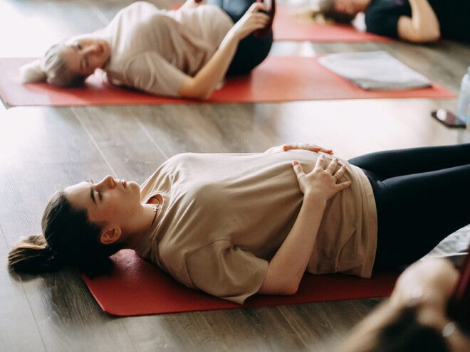 Een vrouw snijdt tomaten op een houten snijplank, omringd door verse groenten en kruiden