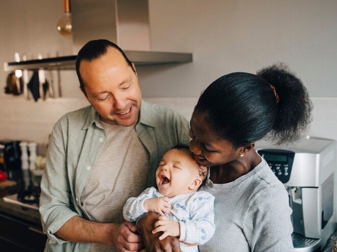 Foto van een lachend stel dat hun baby vasthoudt in de keuken
