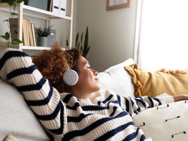 Vrouw ontspant op de bank en luistert met koptelefoon