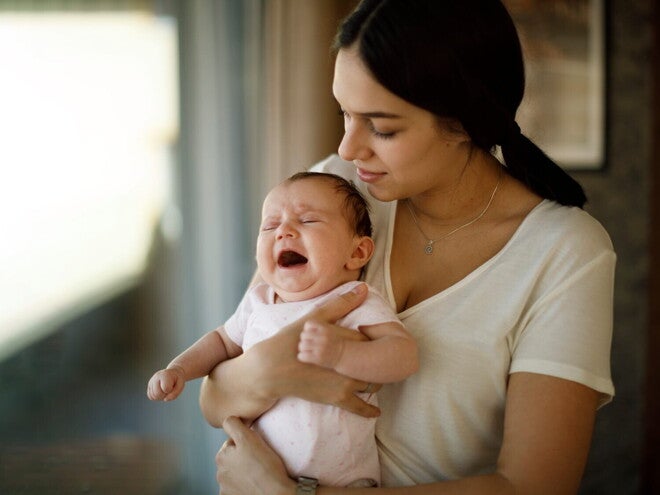 Une femme tient un bébé qui pleure dans ses bras