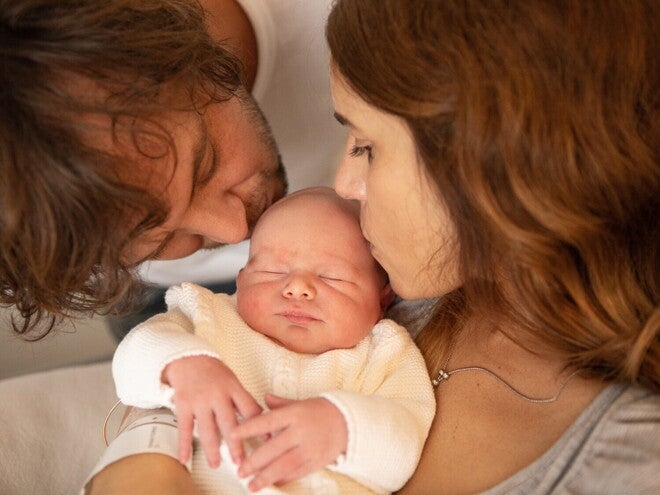 Een man en een vrouw kussen hun baby