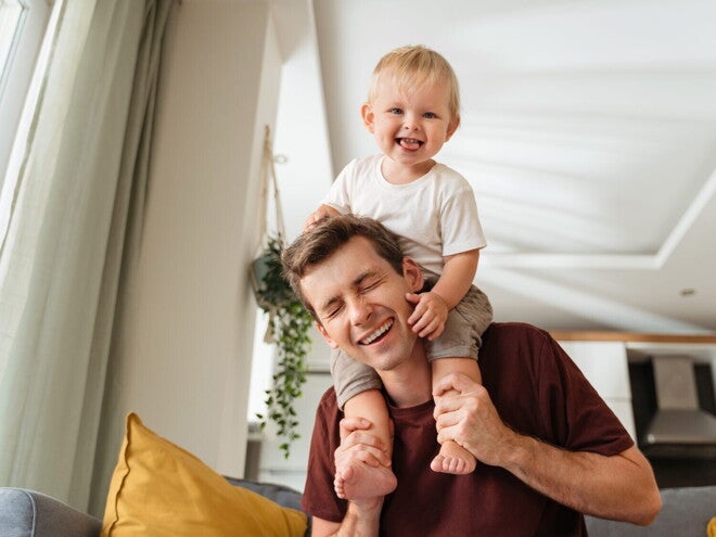 Un homme porte un bébé souriant sur ses épaules