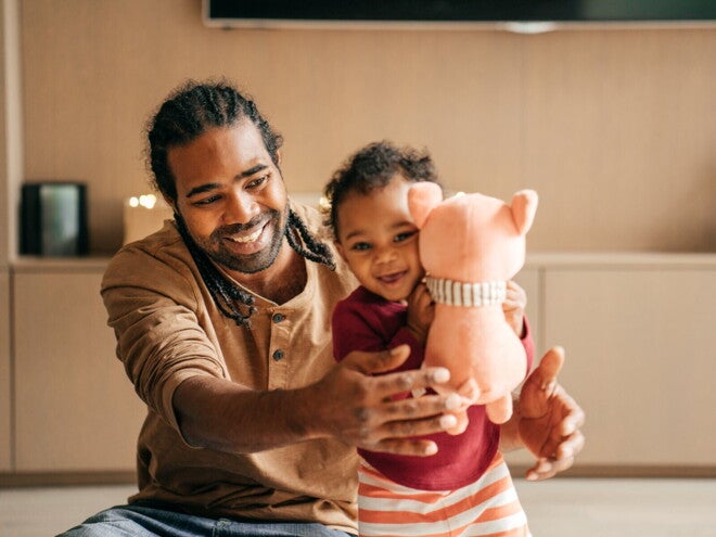 Un père joue avec son tout-petit qui tient une peluche