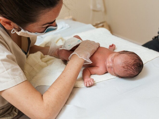Een zorgverlener onderzoekt en verzorgt een pasgeboren baby