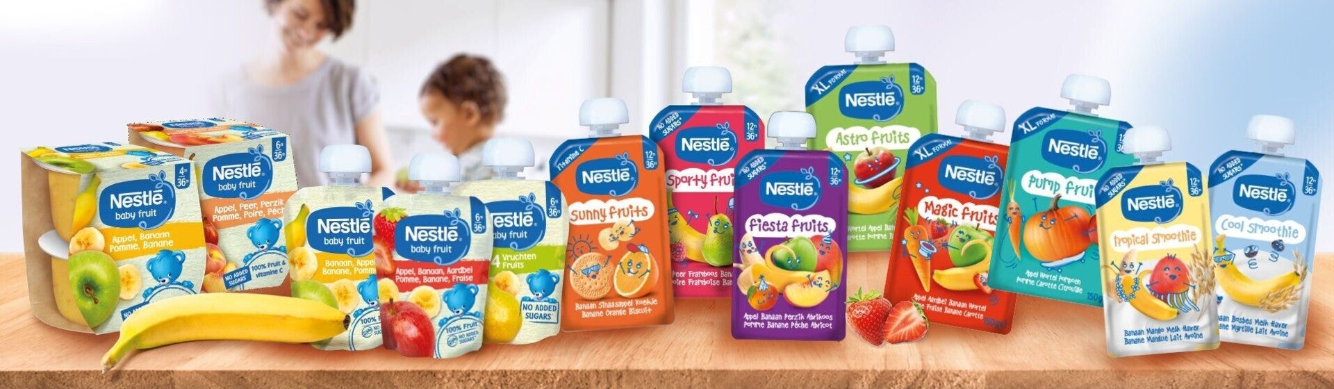 Meerdere Nestlé babyvoedingsproducten staan op een houten tafel.