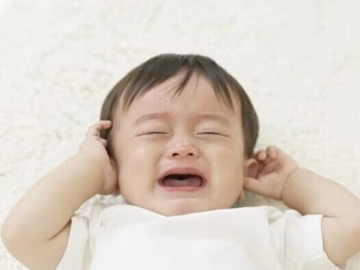 Image bébé pleure en se touchant les oreilles Image bébé pleure en se touchant les oreilles