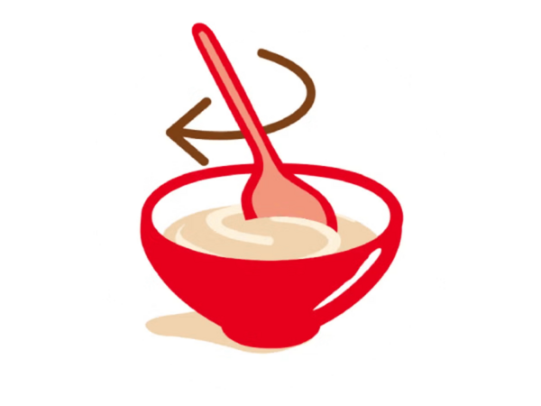 Bol rouge dans lequel une cuillère remue un mélange beige.