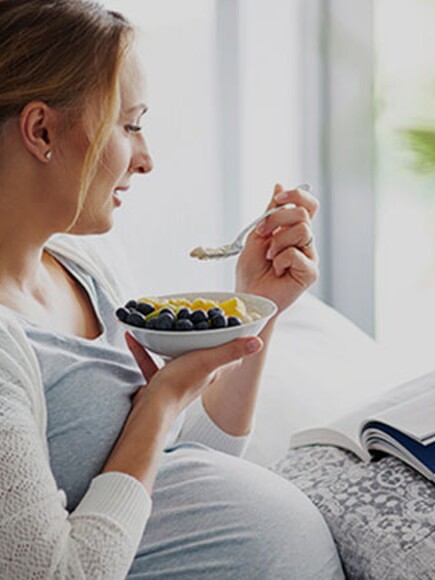 Pregnant woman having fruits while reading